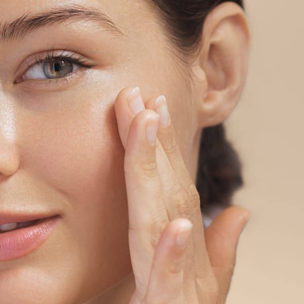 Une femme avec un chemisier blanc et une main blanche touchant son visage.