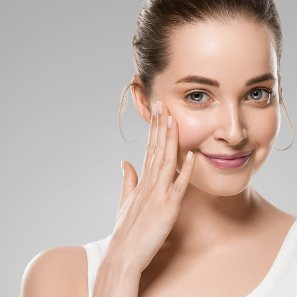 Une femme avec un haut blanc et des produits de soins de la peau.