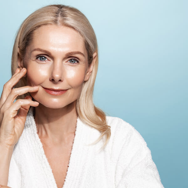 Une femme en peignoir se tenant la main sur le visage.