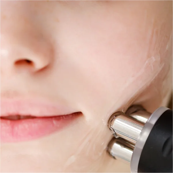 Une femme utilise un appareil facial pour nettoyer son visage avec soin et précision.