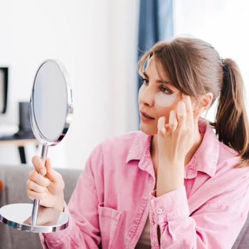 Femme inspectant sa peau dans un miroir de table pour évaluer l'uniformité de son teint après traitement
