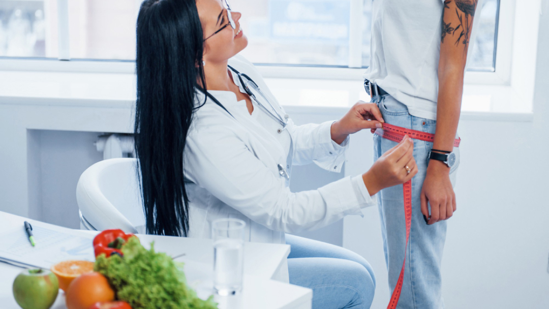 Médecin mesurant le tour de taille d'une patiente lors d'une consultation pour traitement EmSculpt Neo